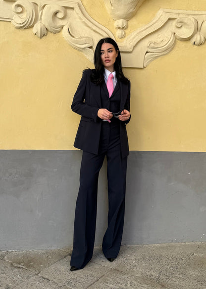giacca monopetto sfiancata, pantaloni navy, camicia bianca e cravatta rosa.