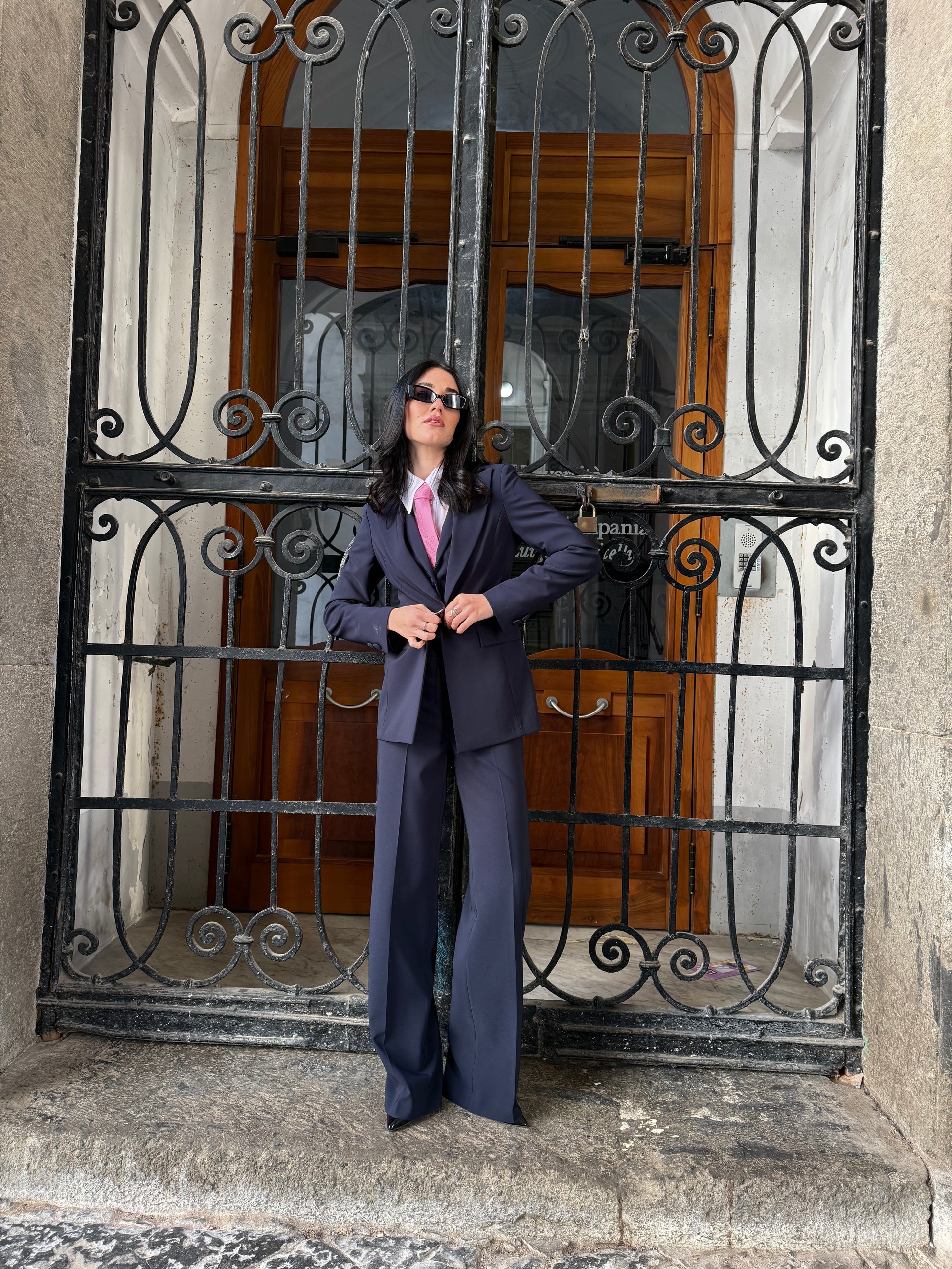 Tailleur donna tre pezzi Made in Italy con giacca monopetto sfiancata, gilet crop e pantalone palazzo, indossato in contesto urbano elegante