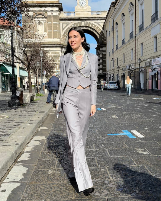 Donna in completo gessato tre pezzi: giacca oversize monopetto, gilet crop e pantaloni palazzo, strada cittadina