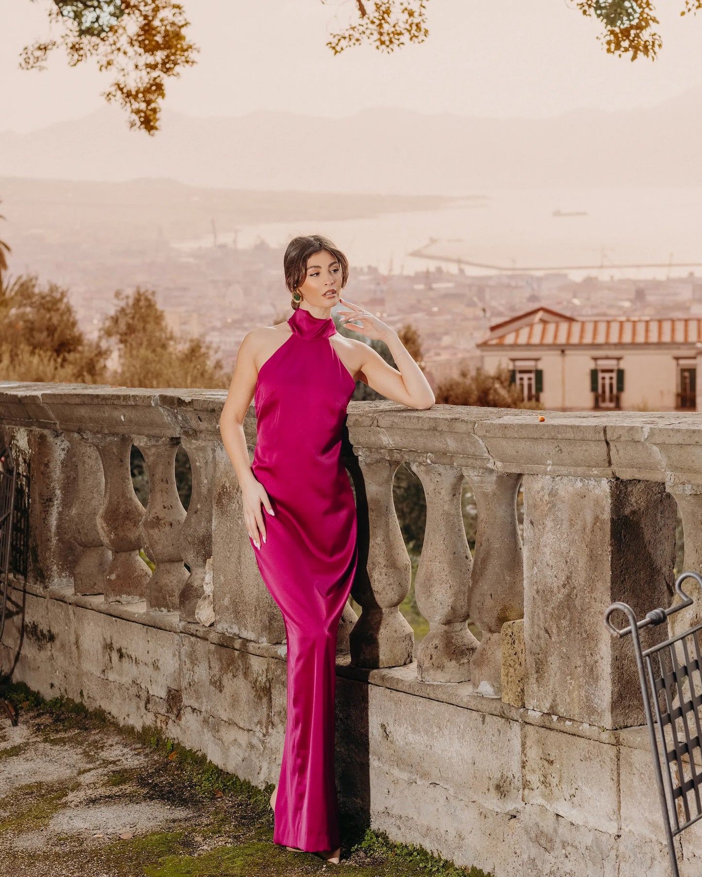 Abito lungo satin fucsia con scollo halter donna elegante – vista frontale ambientata