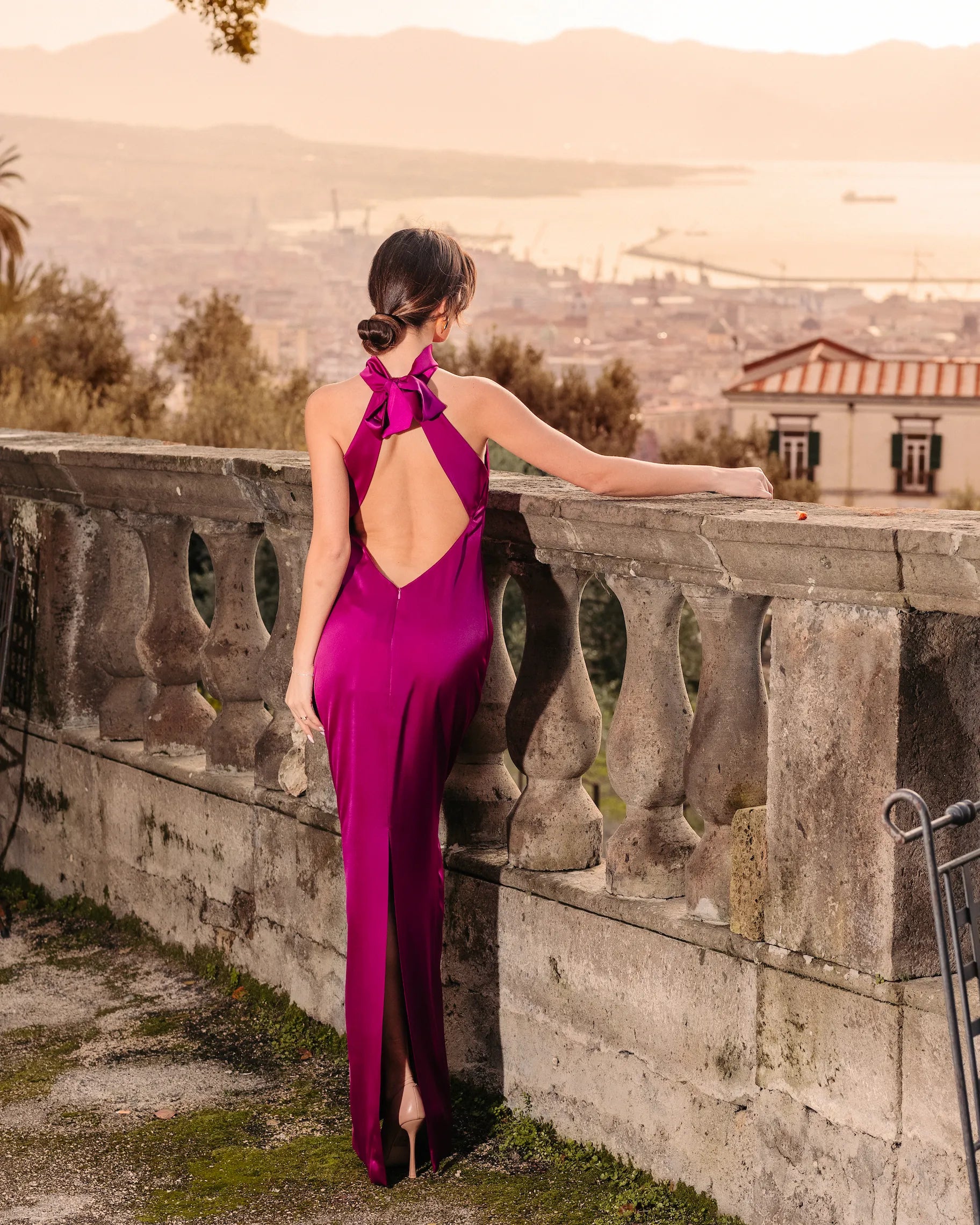 Abito lungo elegante fucsia con schiena scoperta e fiocco posteriore – vista retro ambientata